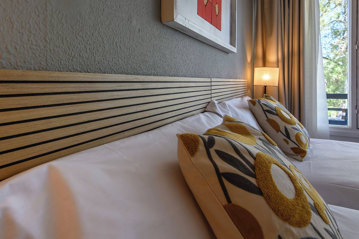 A neatly made bed with a striped headboard, a bedside lamp, and patterned pillows.
