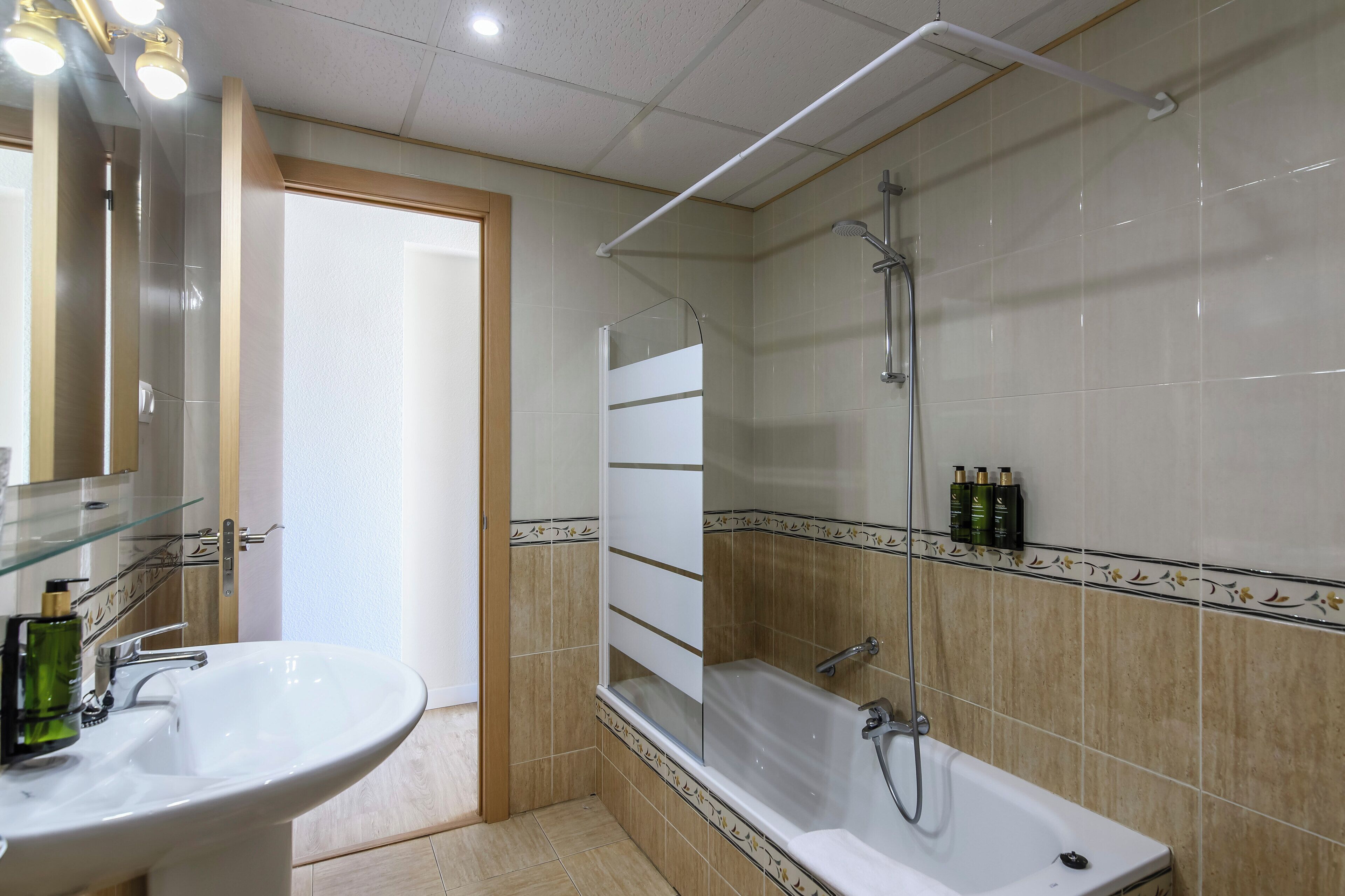 Un baño con lavamanos blanco, cabina de ducha con mampara de vidrio y bañera.