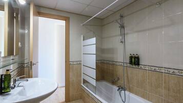 Un baño con lavamanos blanco, cabina de ducha con mampara de vidrio y bañera.