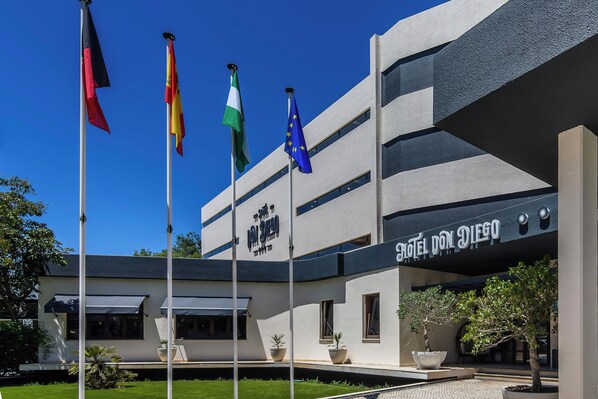 A hotel with a modern facade, multiple flags, and a clear sky. - HOTEL DON DIEGO by Ĥ (Ayamonte)