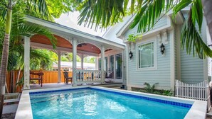 A swimming pool with a wooden deck and a covered patio area. - Casa De Cubana | New! Cuban-Style Home Near Duval (Key West)