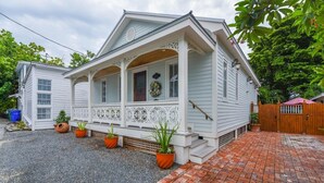 A white house with a porch, brick pathway, and potted plants. - Casa De Cubana | New! Cuban-Style Home Near Duval (Key West)
