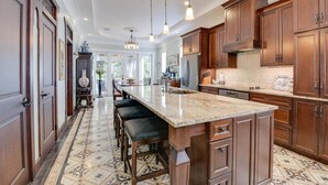 A spacious kitchen with a large island, wooden cabinets, and a patterned floor. - Casa De Cubana | New! Cuban-Style Home Near Duval (Key West)