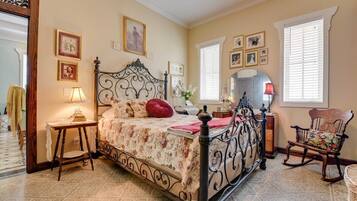 Une chambre à coucher avec un lit à baldaquin, une chaise en bois, une petite table avec une lampe et un miroir au mur.