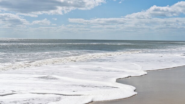 Een strand met golven en een heldere lucht.