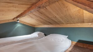 Une pièce avec un plafond en bois et un lit recouvert de draps blancs.