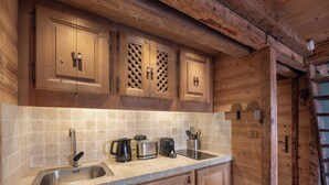Une cuisine en bois avec un dosseret carrelé, un évier en acier inoxydable et des armoires en bois.