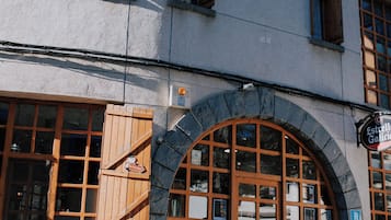 Un edificio con fachada de piedra, contraventanas de madera y un amplio ventanal de arco.