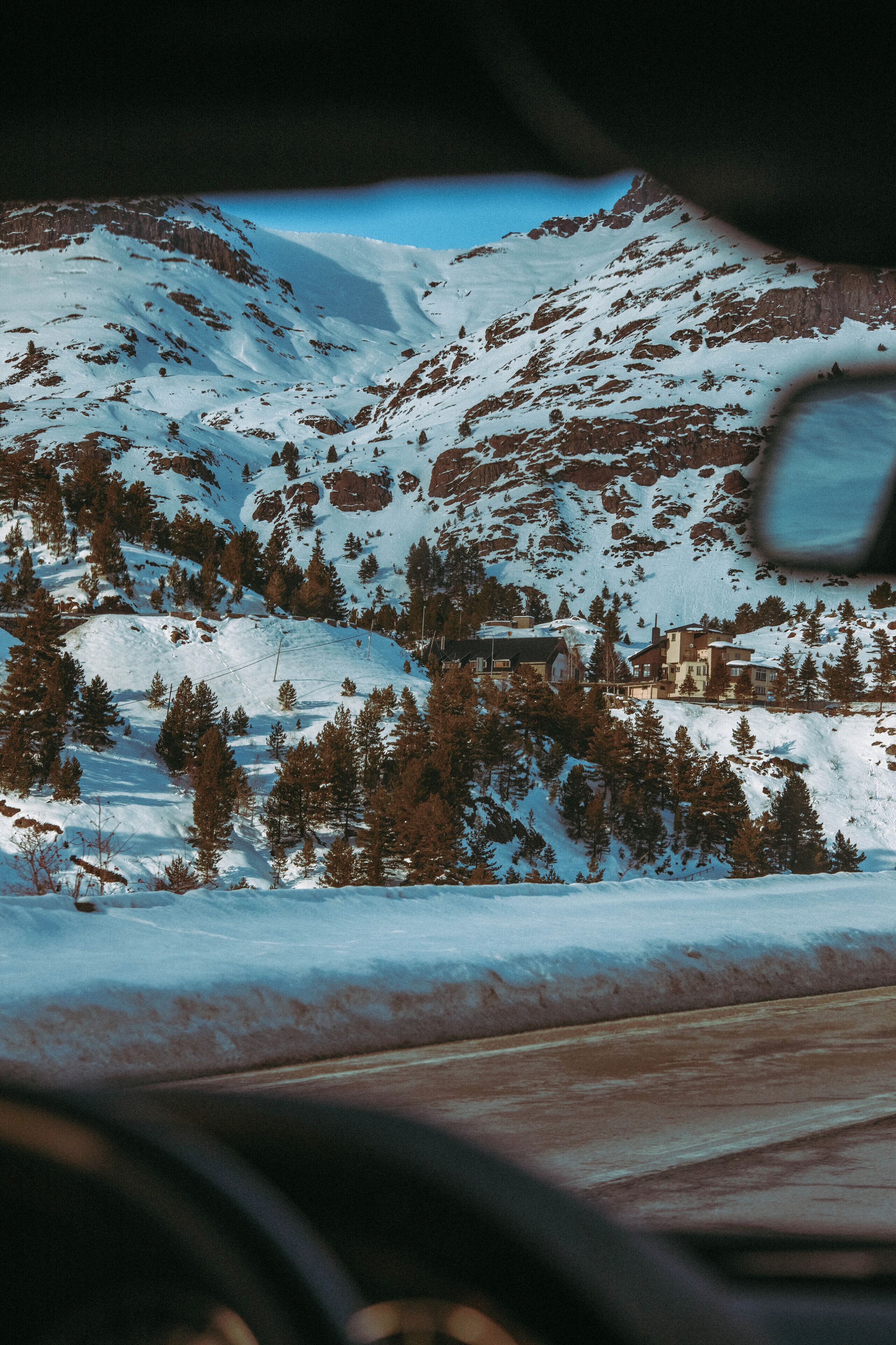 A snow-covered mountain with a cabin and trees.