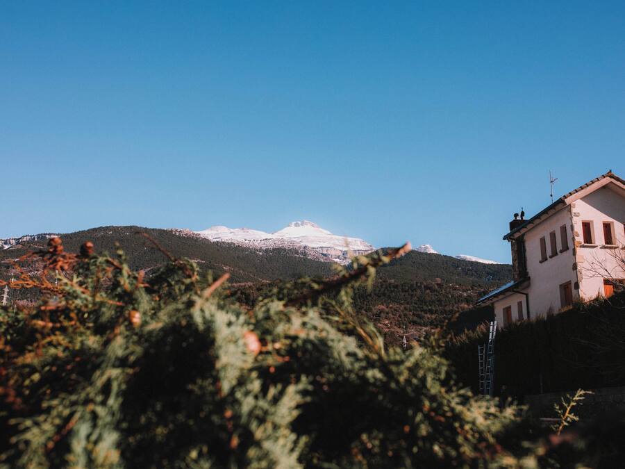 A mountain with snow-capped peaks and a building with a sloped roof.