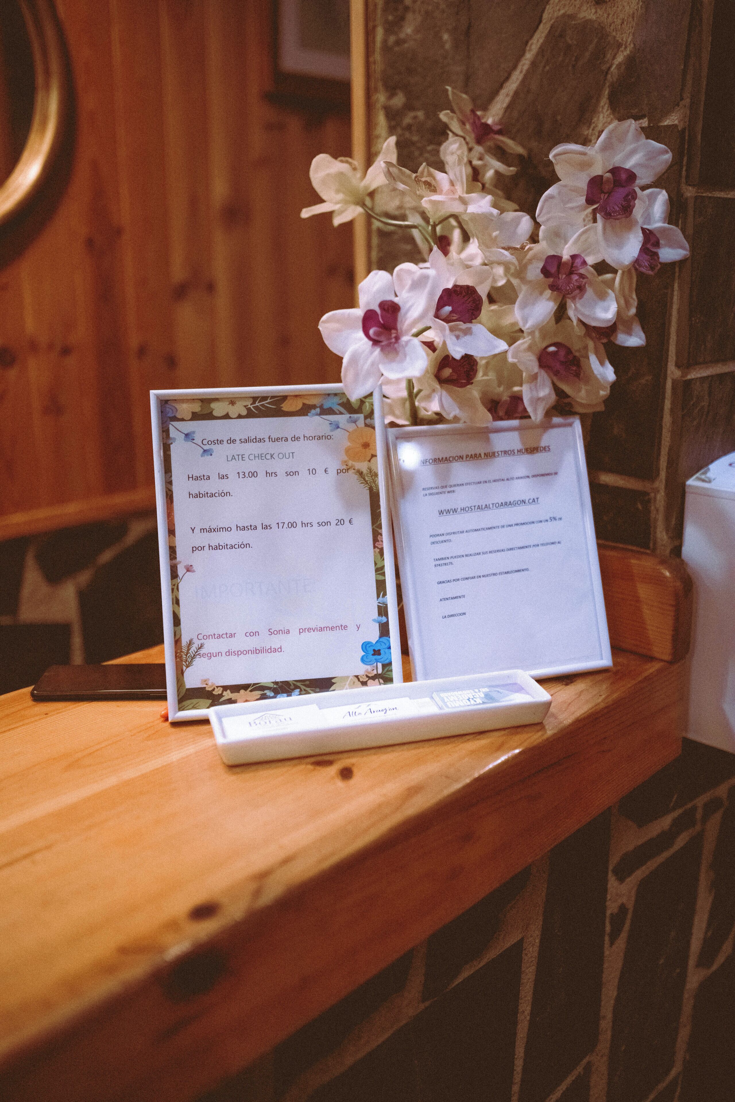 A wooden table with a framed sign and a vase of white orchids.