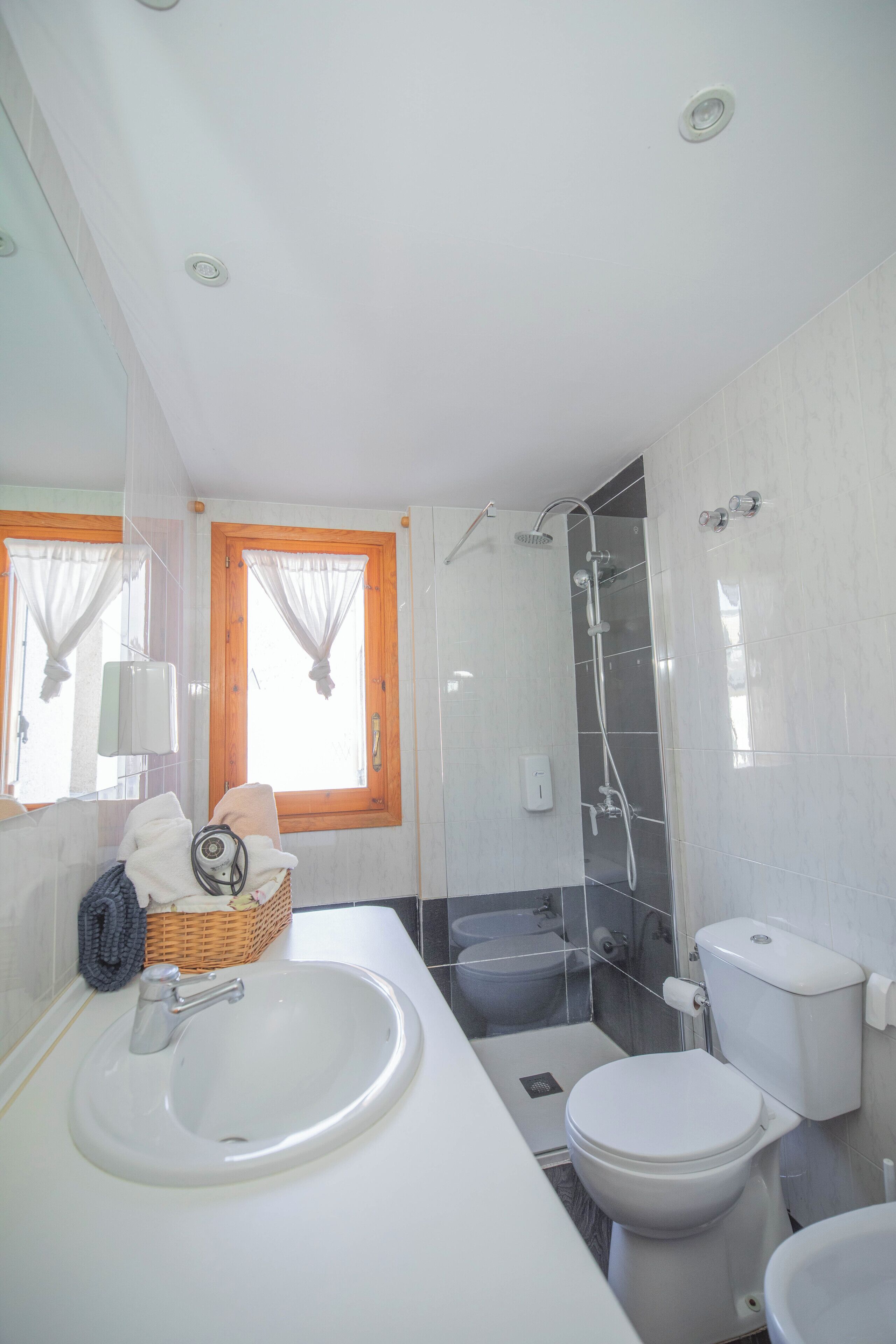 Et moderne badeværelse med vask, toilet og bruser.