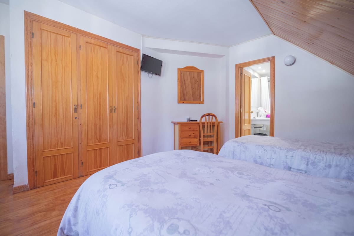 Ein Schlafzimmer mit zwei Betten, einem Holzschrank, einem Fernseher und einem Spiegel.