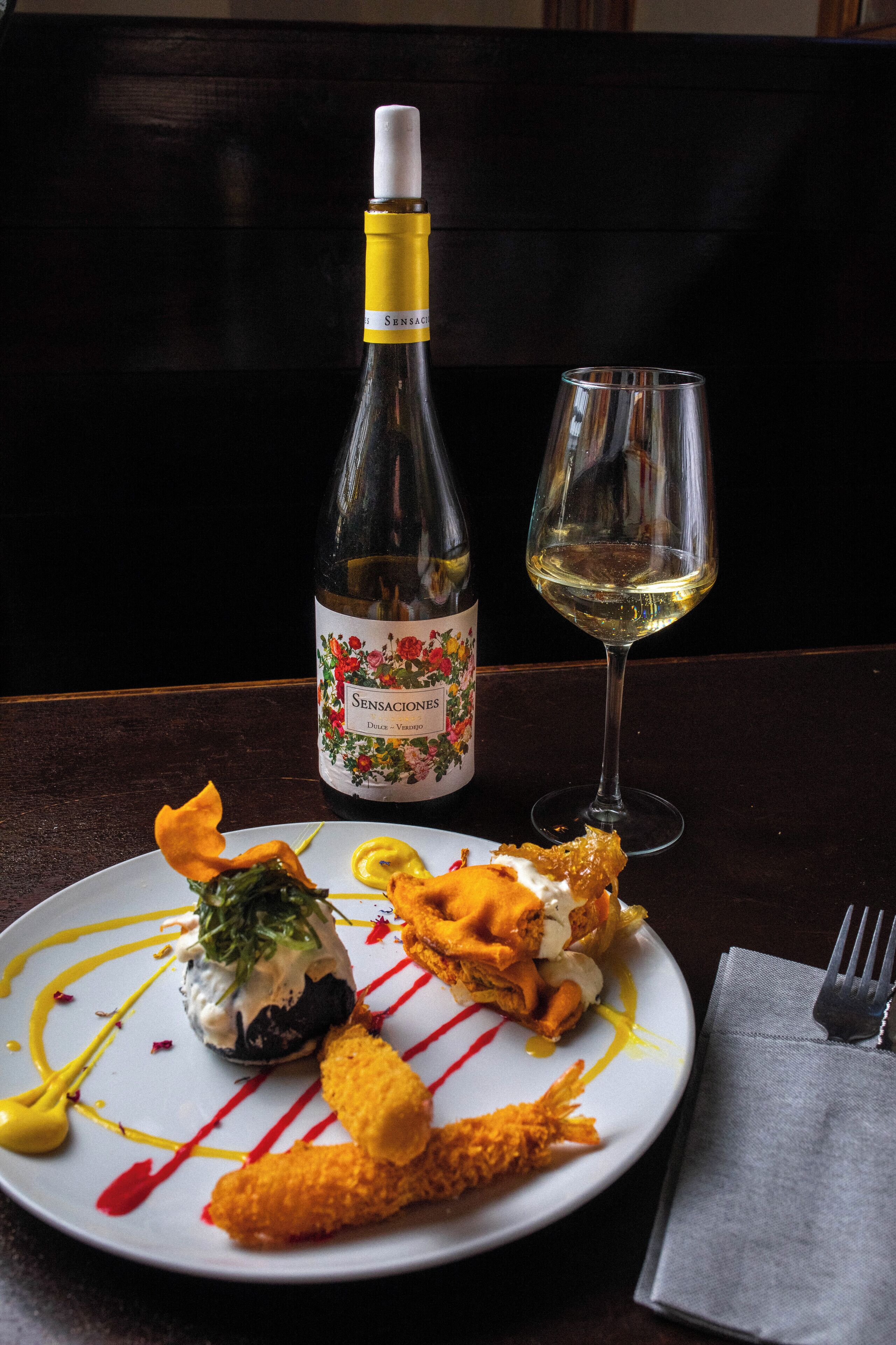 Un plato de comida con una botella de vino y una copa sobre una mesa.