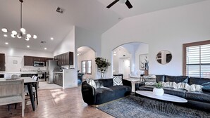 A spacious living area with a black sofa, a coffee table, and a dining table. - 5 Bdrm Entertainers Dream Home.  Game Room, HTD Pool and Backyard Oasis! (Scottsdale)