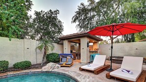A backyard with a swimming pool, lounge chairs, a red umbrella, and a barbecue area. - 5 Bdrm Entertainers Dream Home.  Game Room, HTD Pool and Backyard Oasis! (Scottsdale)