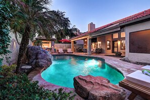 A swimming pool with a stone border, surrounded by lounge chairs and a covered patio area. - 5 Bdrm Entertainers Dream Home. Game Room, HTD Pool and Backyard Oasis! (Scottsdale)