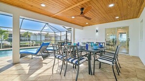An outdoor patio with a pool, lounge chairs, a dining table, and chairs. - Waterfront 3-Bed Home in SW Cape Heated Saltwater Pool, Boat Dock, Kayaks, Bikes (Cape Coral)