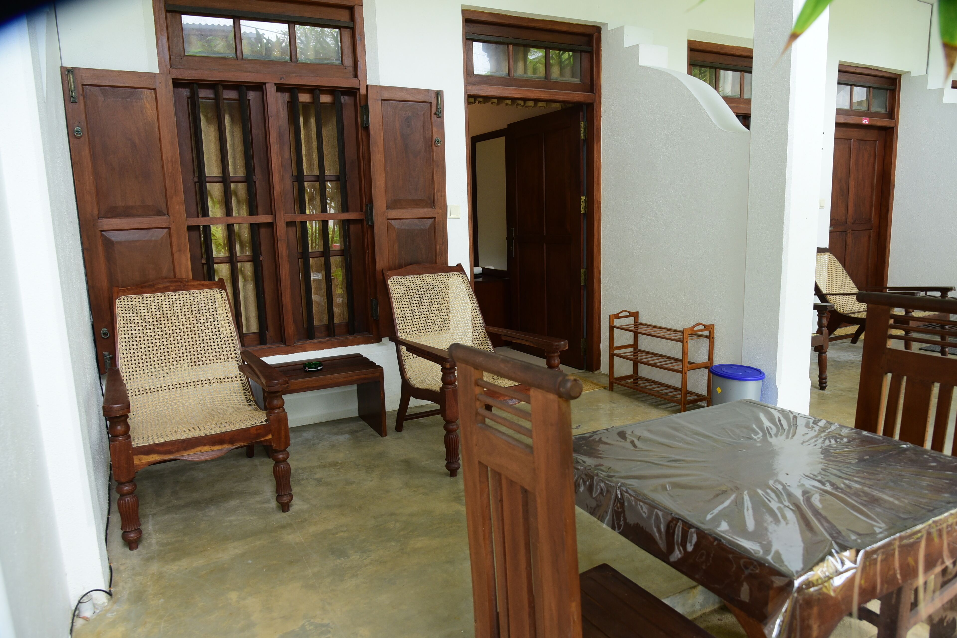Una habitación con muebles de madera, incluyendo sillas y una mesa, y una ventana con contraventanas de madera.
