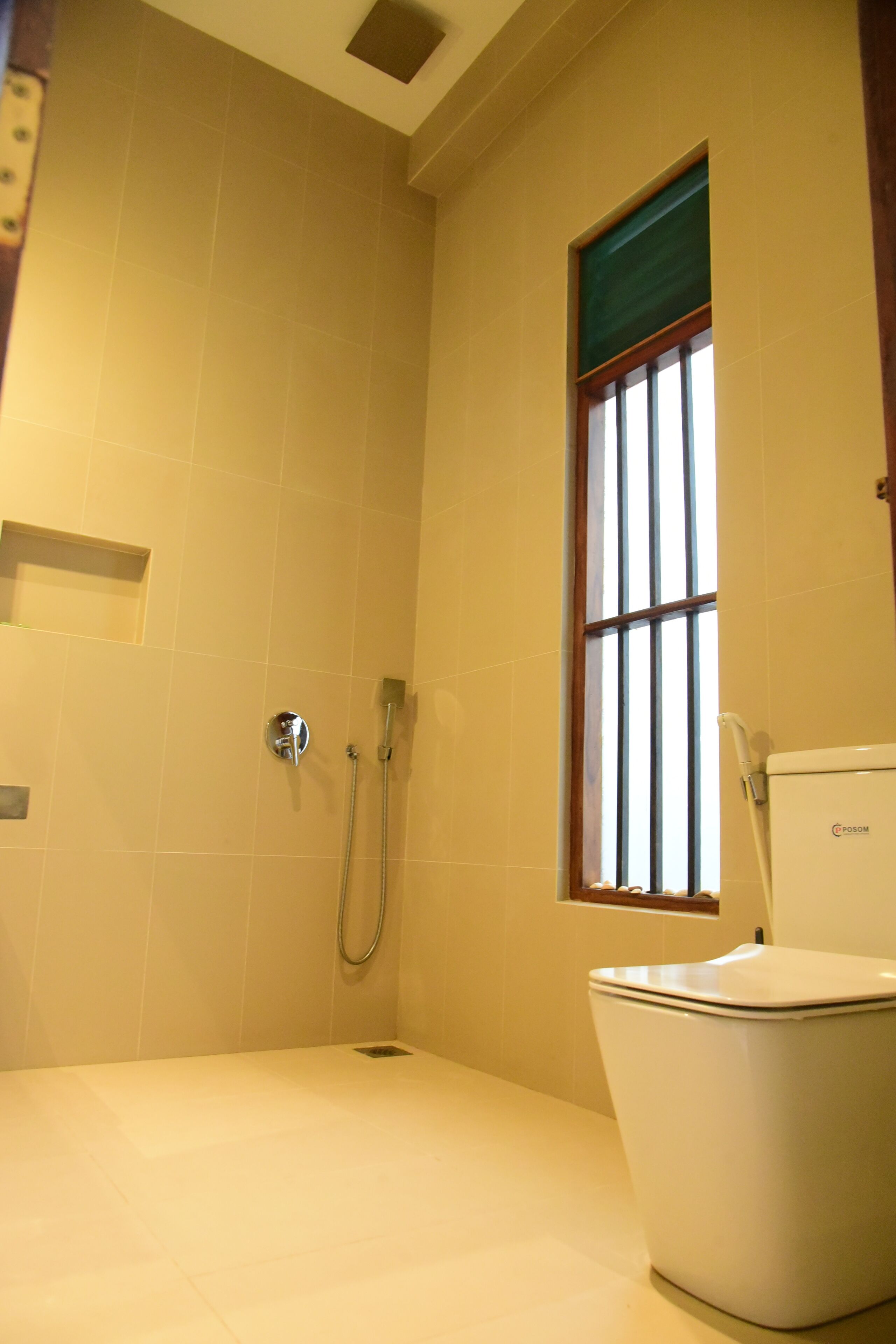 A bathroom with a shower, toilet, and a window with bars.