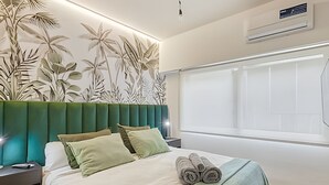 A neatly made bed with green and white bedding, a headboard with a leaf pattern, and a window with blinds. - Spacious with Terrace and Private BBQ in Belgrano (Buenos Aires)