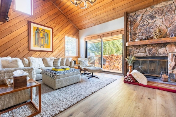 Warm and inviting living room with vaulted wood ceilings, a stone fireplace, and plush sectional seating, perfect for cozy nights after a day on the slopes.