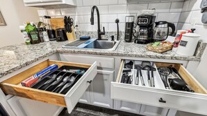 A kitchen with a granite countertop, a coffee maker, a toaster, and a drawer organizer with utensils. - AT&T & In the heart of it ALL! (Arlington)