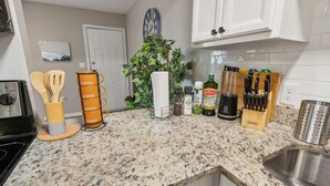 A kitchen with granite countertops, a coffee station, a clock, and various kitchen utensils. - Prime 1BD Close to the Action (Arlington)