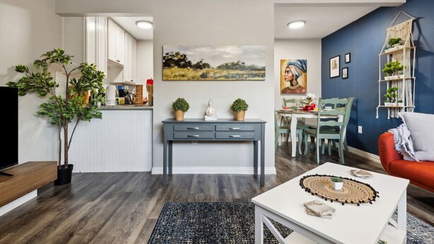 A modern living room with a dining area, a kitchen, and a blue accent wall. - Prime 1BD Close to the Action (Arlington)
