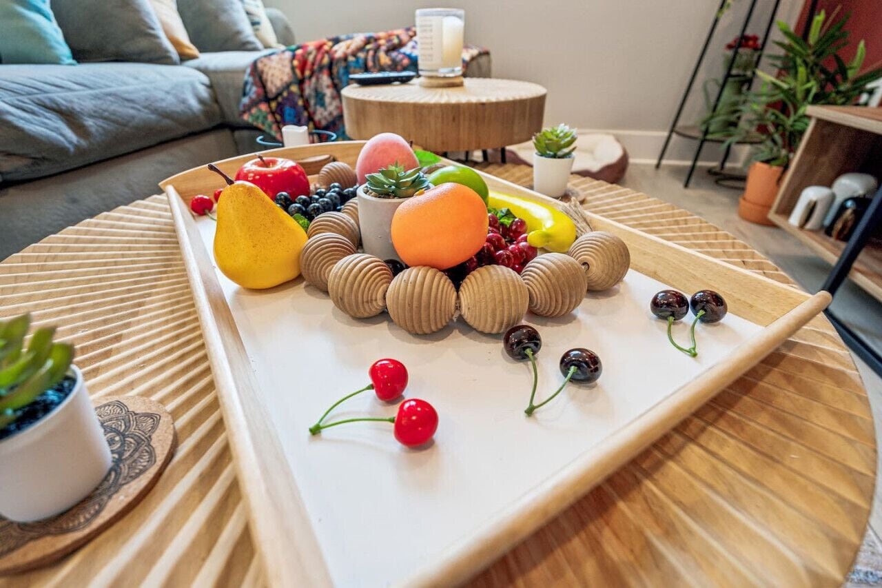 A tray of assorted fruits and a small succulent plant on a wooden table in a living room.