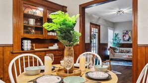 A dining room with a round table, white chairs, a chandelier, and wooden cabinetry. - This is Your Home Away From Home! Warm & Comfy 2BD (Fort Worth)