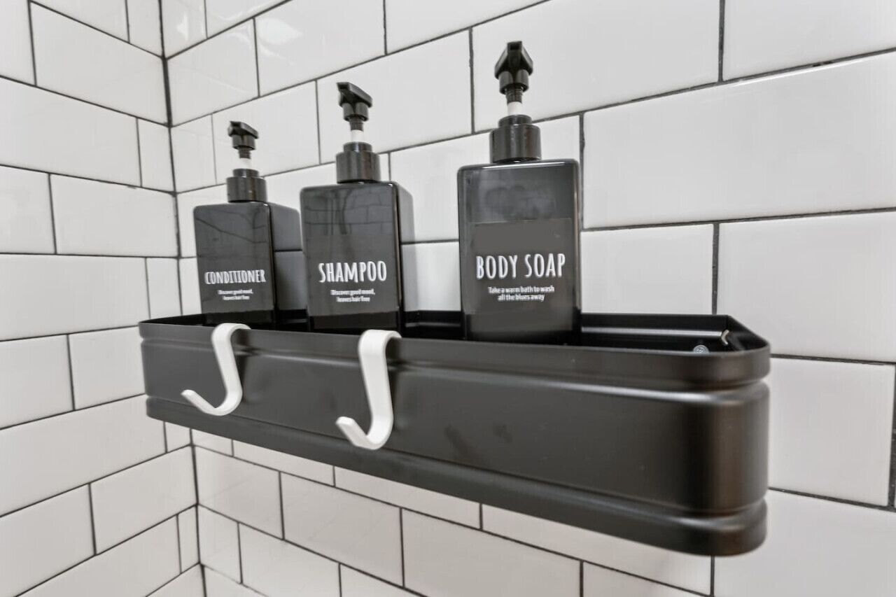 Een badkamerschaar met drie verzorgingsproducten: conditioner, shampoo en douchegel.