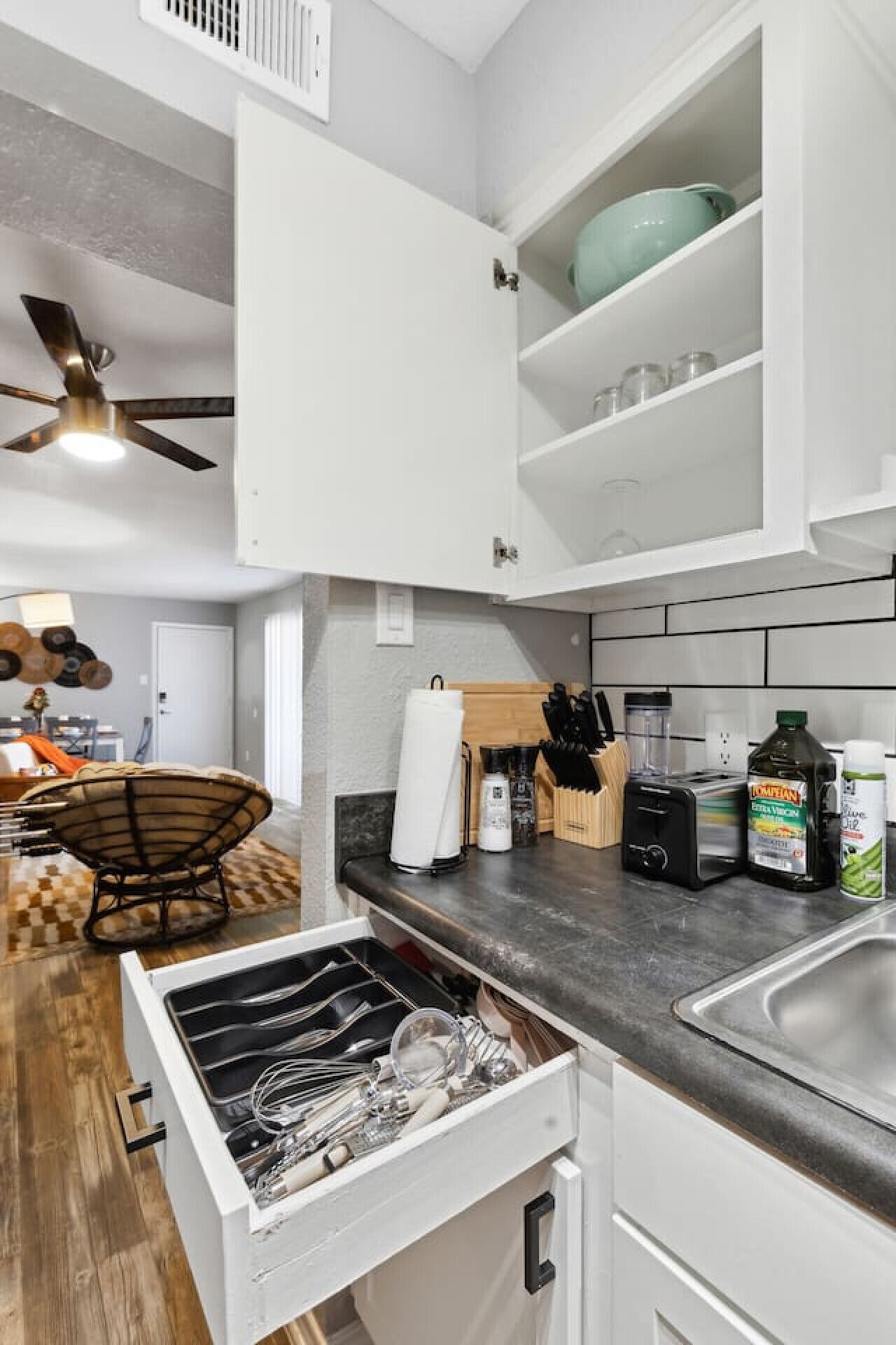 Uma cozinha moderna com armários brancos, máquina de lavar louça embutida e bancada com torradeira e cafeteira.