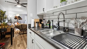 Una cocina moderna con una paleta de colores blanco y negro, que incluye un lavamanos doble, un grifo de acero inoxidable y una variedad de utensilios de cocina.