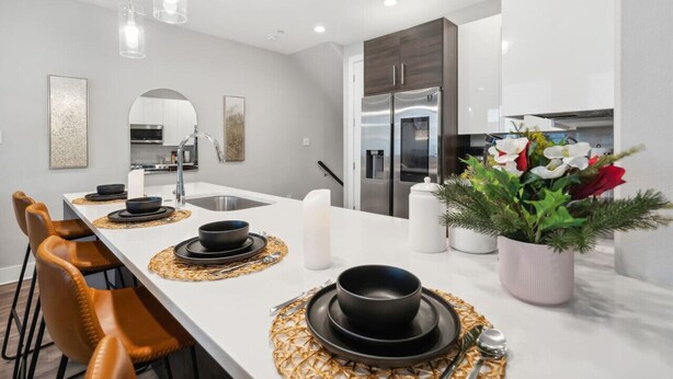 A modern kitchen with white countertops, stainless steel appliances, and a central island with seating. - The Charm :2BD In the Heart of Magnolia & Stylish! (Fort Worth)