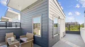 A modern building with a balcony featuring wicker furniture and a glass table. - The Charm :2BD In the Heart of Magnolia & Stylish! (Fort Worth)