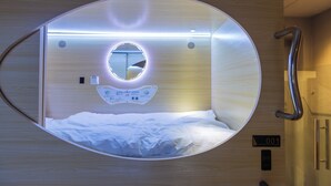 A circular room with a bed, a mirror, and a control panel. - Resthub (George Town)