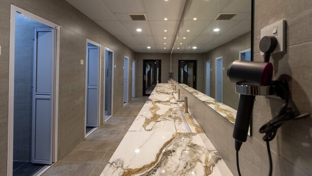 A hotel corridor with marble flooring, multiple doors, and a hairdryer mounted on the wall. - Resthub (George Town)
