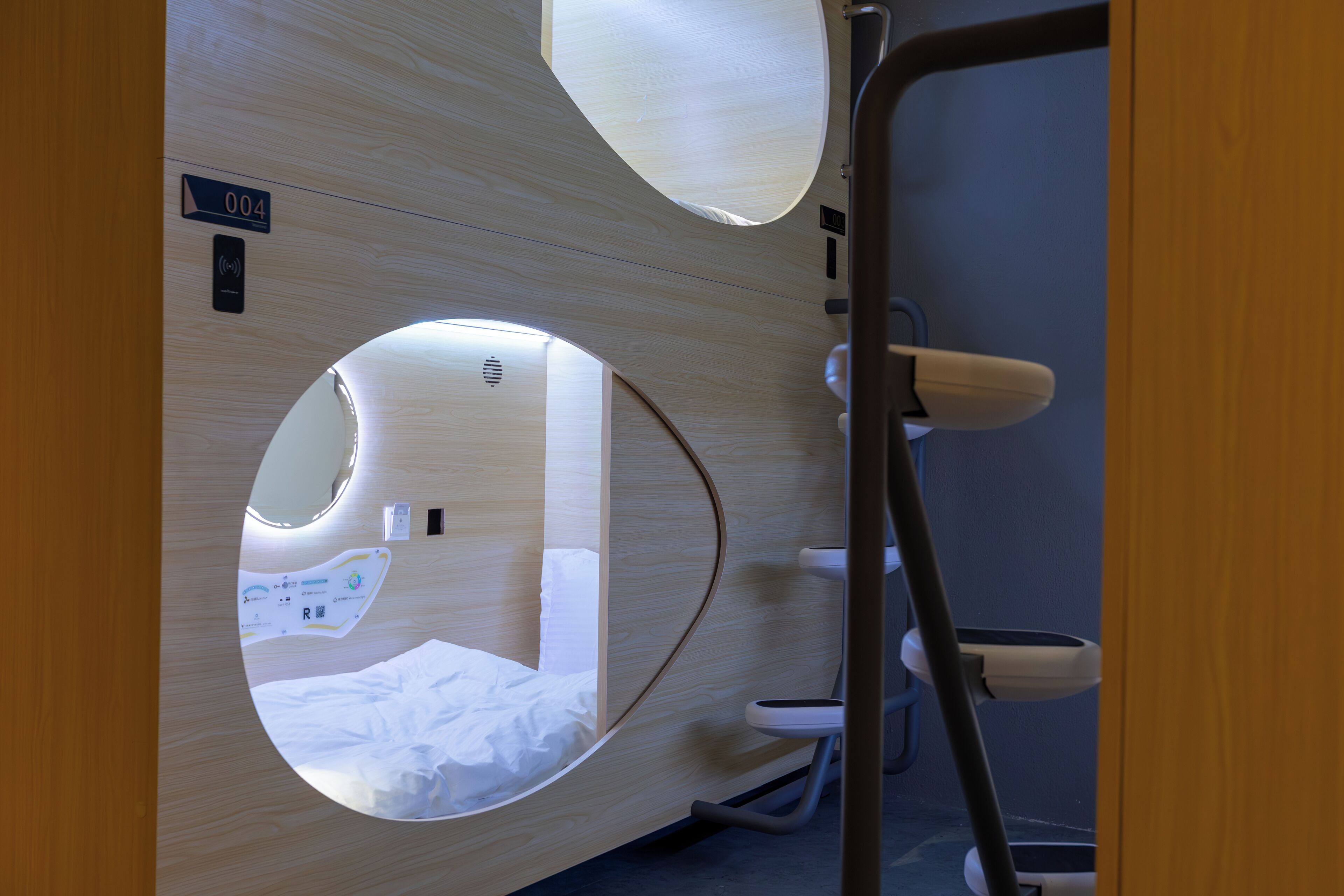 A modern room with a circular mirror, a bed, a toilet, and a small sink.