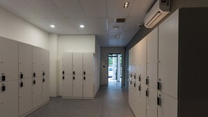 A hallway with lockers, a brick wall, and a door leading to another area. - Resthub (George Town)