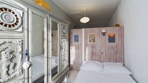 A bedroom with a bed, a wardrobe, and a wooden wall with framed pictures.