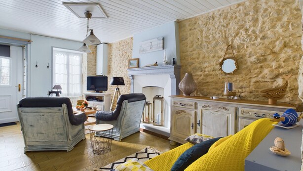 A living room with a fireplace, a television, and a stone wall.