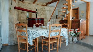 A dining area with a wooden table and chairs, a stone wall, and a staircase. - Dordogne - Beautiful cottage for 8 with a pool (Saint Rabier)