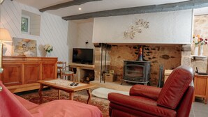 A cozy living room with a fireplace, wooden furniture, and a television. - Dordogne - Beautiful cottage for 8 with a pool (Saint Rabier)