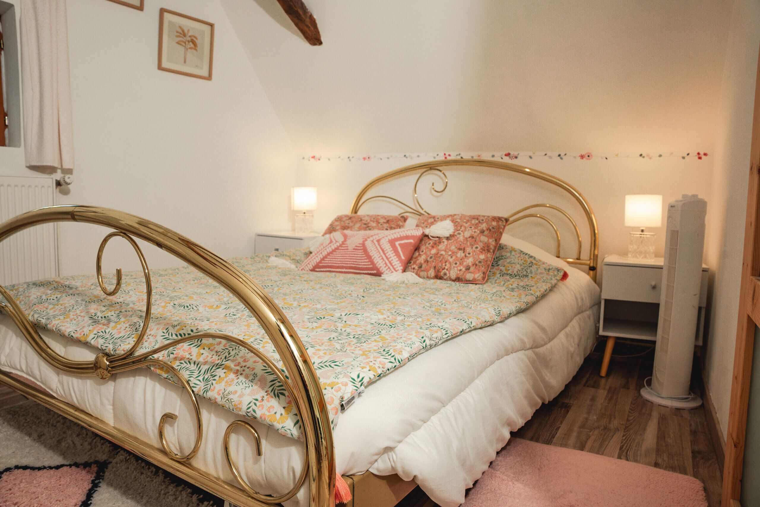 A bedroom with a bed, nightstands, a heater, and a wall with a floral border.