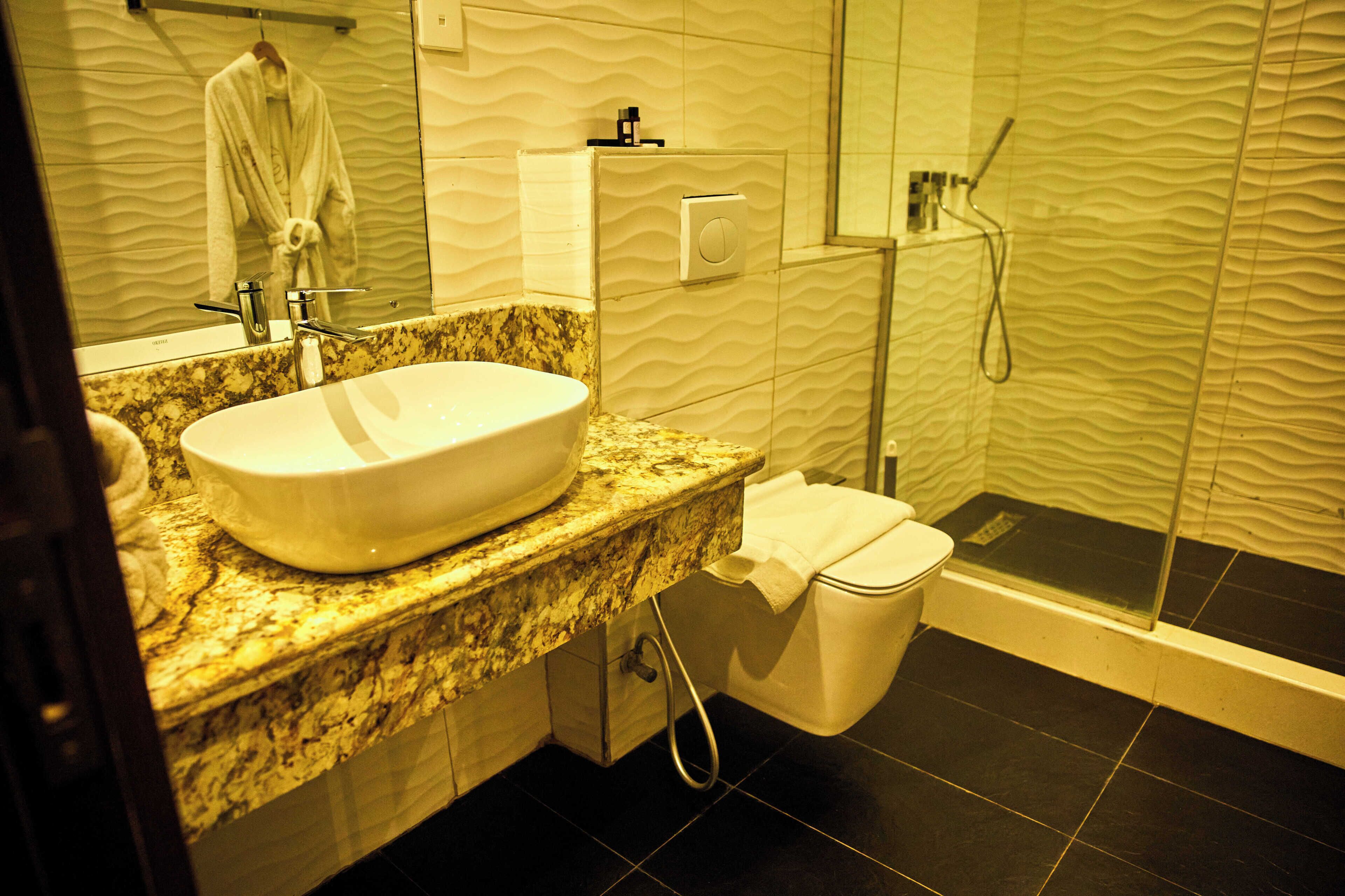 Un baño con lavamanos de mármol, cabina de ducha con vidrio y un perchero para toallas.