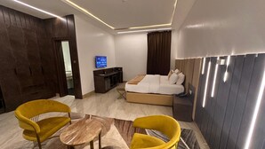 A modern hotel room with a bed, a desk, a TV, and two yellow chairs. - Lunar Signature Hotel & Suites  (Enugu)
