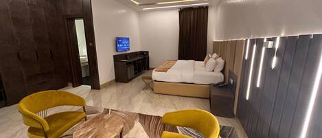 Una habitación de hotel moderna con una cama, un escritorio, un televisor y dos sillas amarillas.