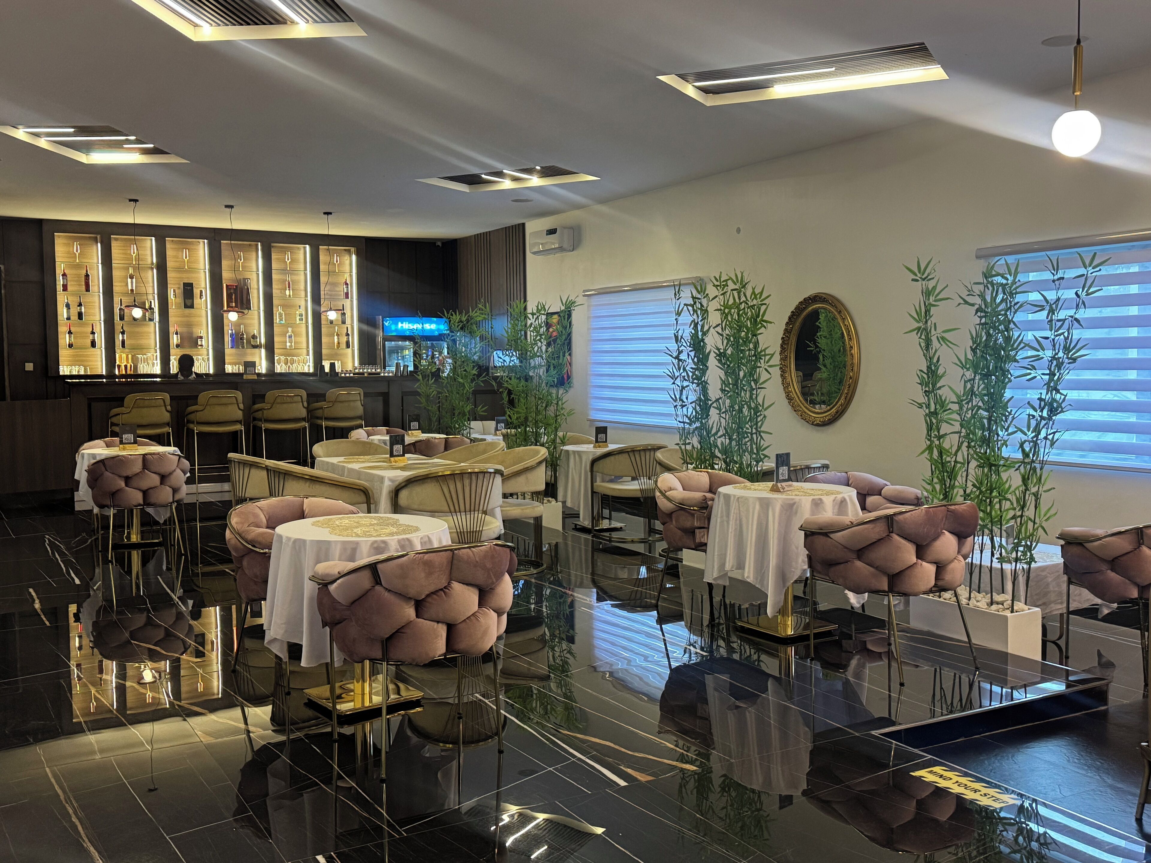 A modern restaurant with a bar area, round tables, and chairs.