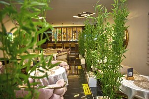 Zona de bar con asientos y barra, rodeada de plantas y un letrero de advertencia.
